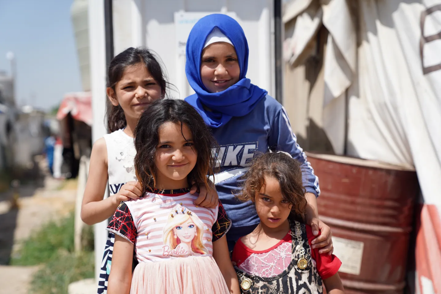 Merhje's four daughters stand in front of their new toilet, a steel structure with a solid door.