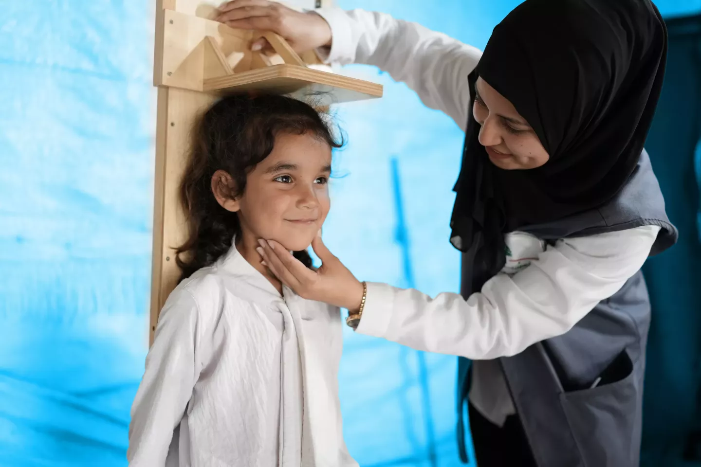 LIMA survey team individual measuring the height of a young girl