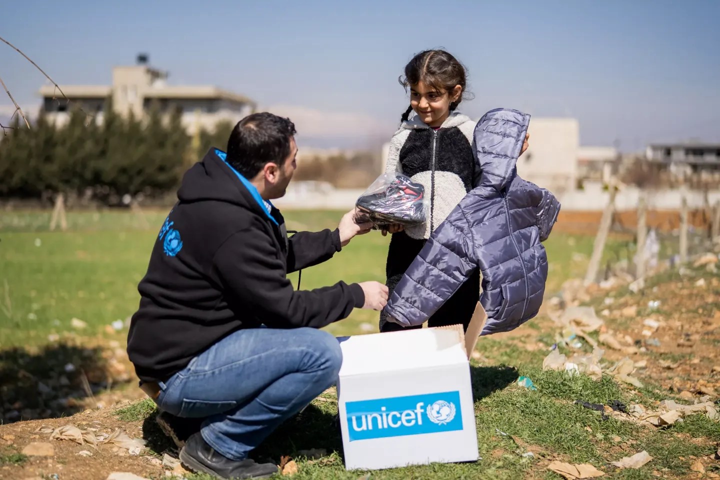 UNICEF Staff giving winter kit to a child 