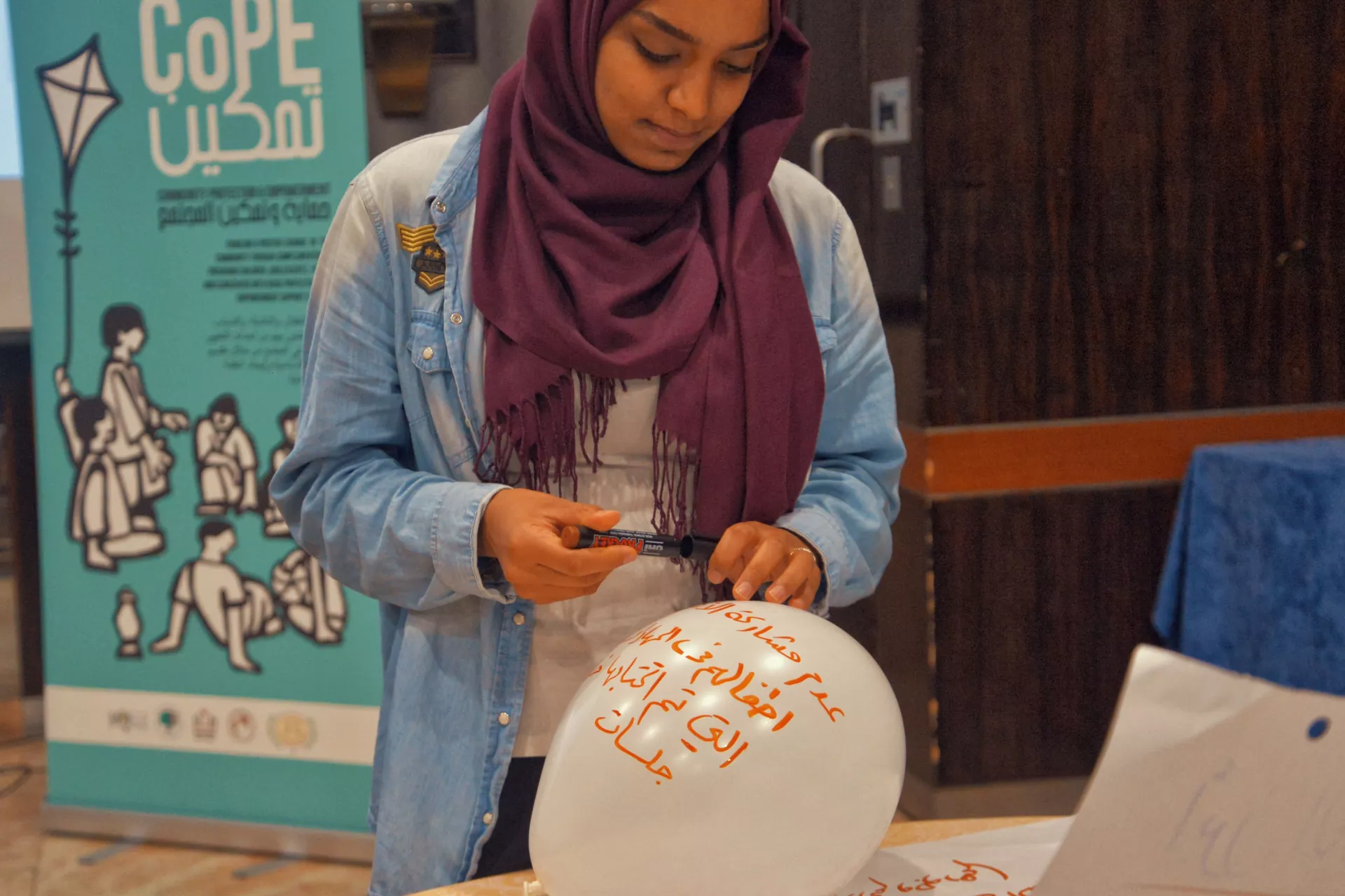 A Palestinian girl at CoPE event writing on a balloon