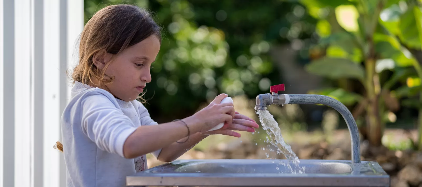 Child washing her hands with clean water