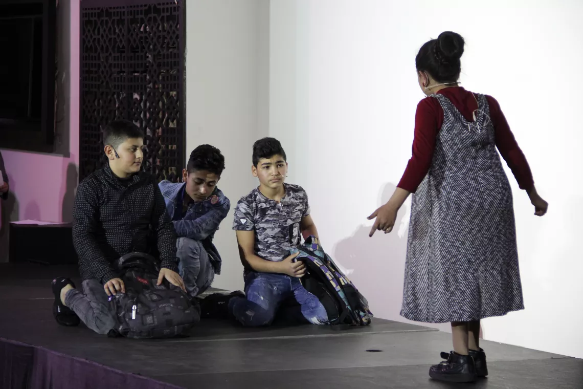During the play, Rimas,10, plays a teacher who yells at a student who arrived late to class due to family issues, demonstrating careless negative behavior of teachers toward children.
