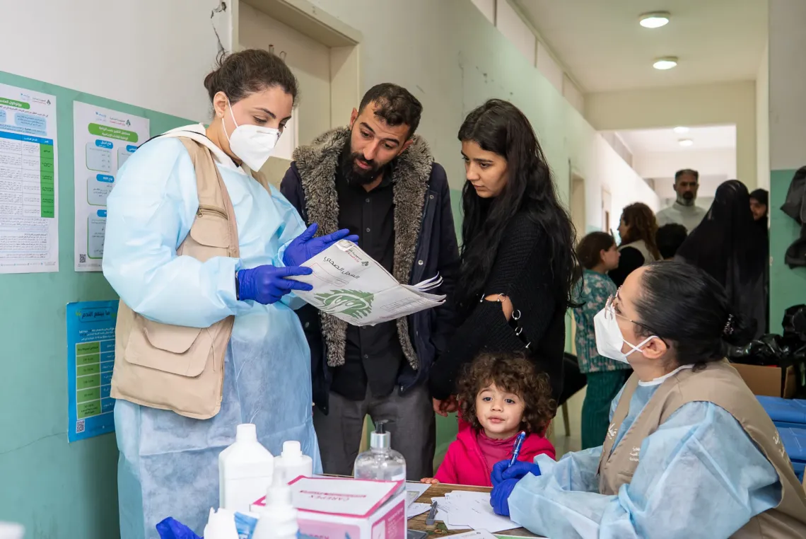 Health workers talking to families at a school shelter 