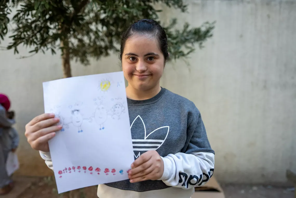 Aya, 17 years old, holding a sketch that she drew 