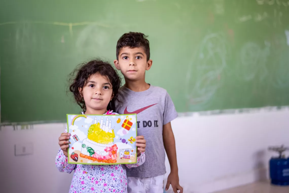 Ahmad 7 years old and his sister Nour, 4 at a school shelter holding their painting 