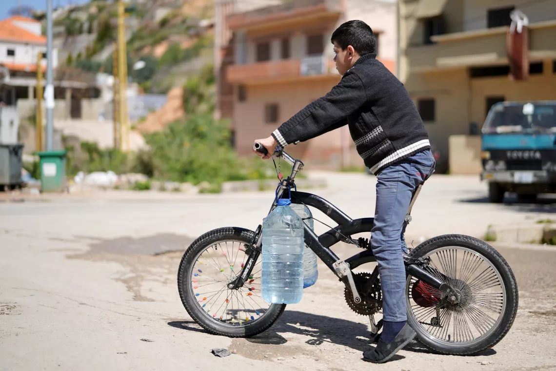 Adham, 11 years old on his bike transporting water 