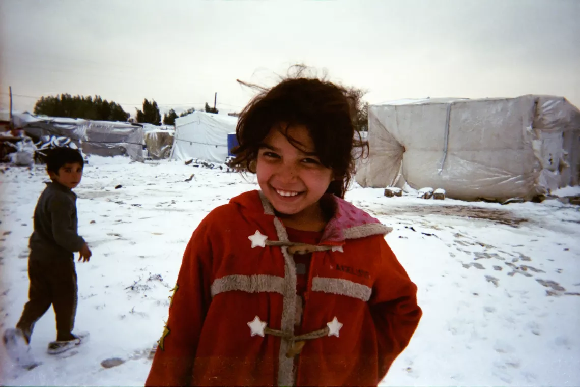 Syrian refugee girl smiling while walking in the snow.