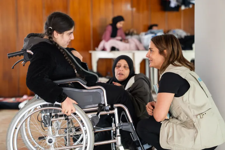 Girl with disability talking to UNICEF staff at a shelter