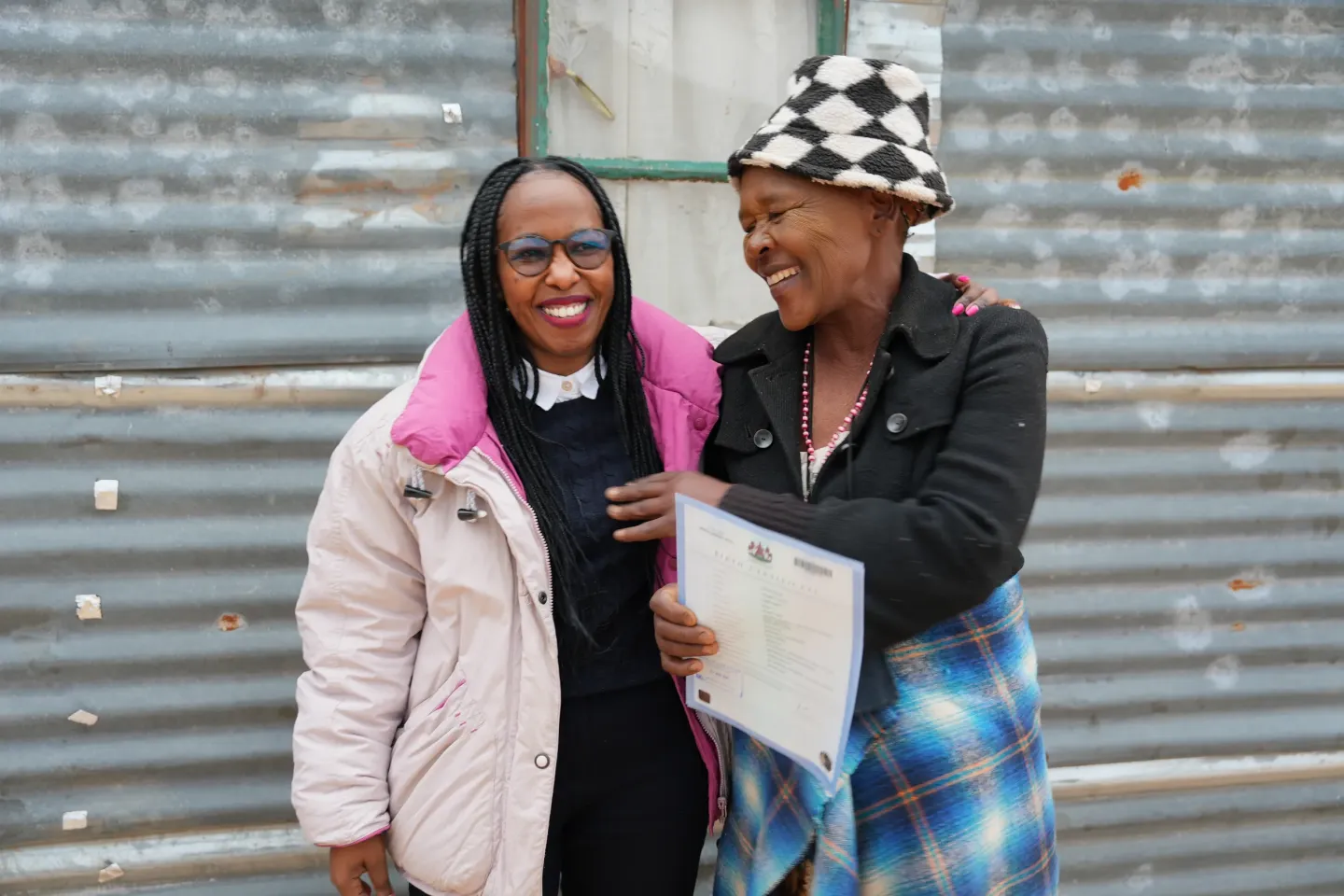 Two women smiling, one holding a certificate