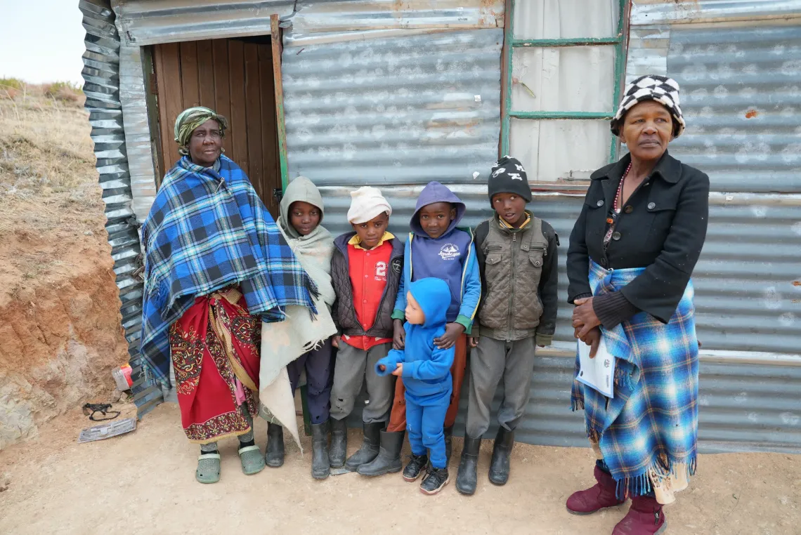 A group of people stand outside the door of their home