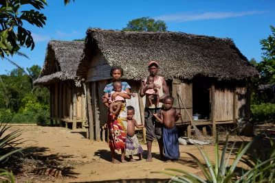 Portrait de Soa et de sa famille debout devant leur maison.