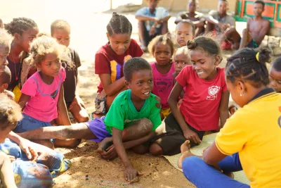 Etsiharogne, au milieu, &eacute;crivant les lettres au sol sous le regard des autres enfants du village.