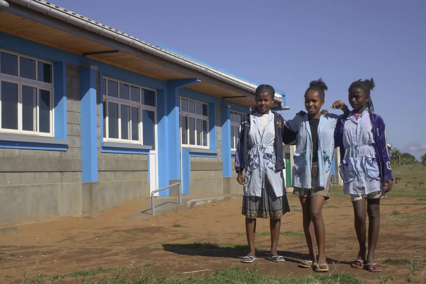 Oliva et ses amies, fi&egrave;res et souriantes, devant le nouveau b&acirc;timent o&ugrave; elles suivent d&eacute;sormais leurs cours.