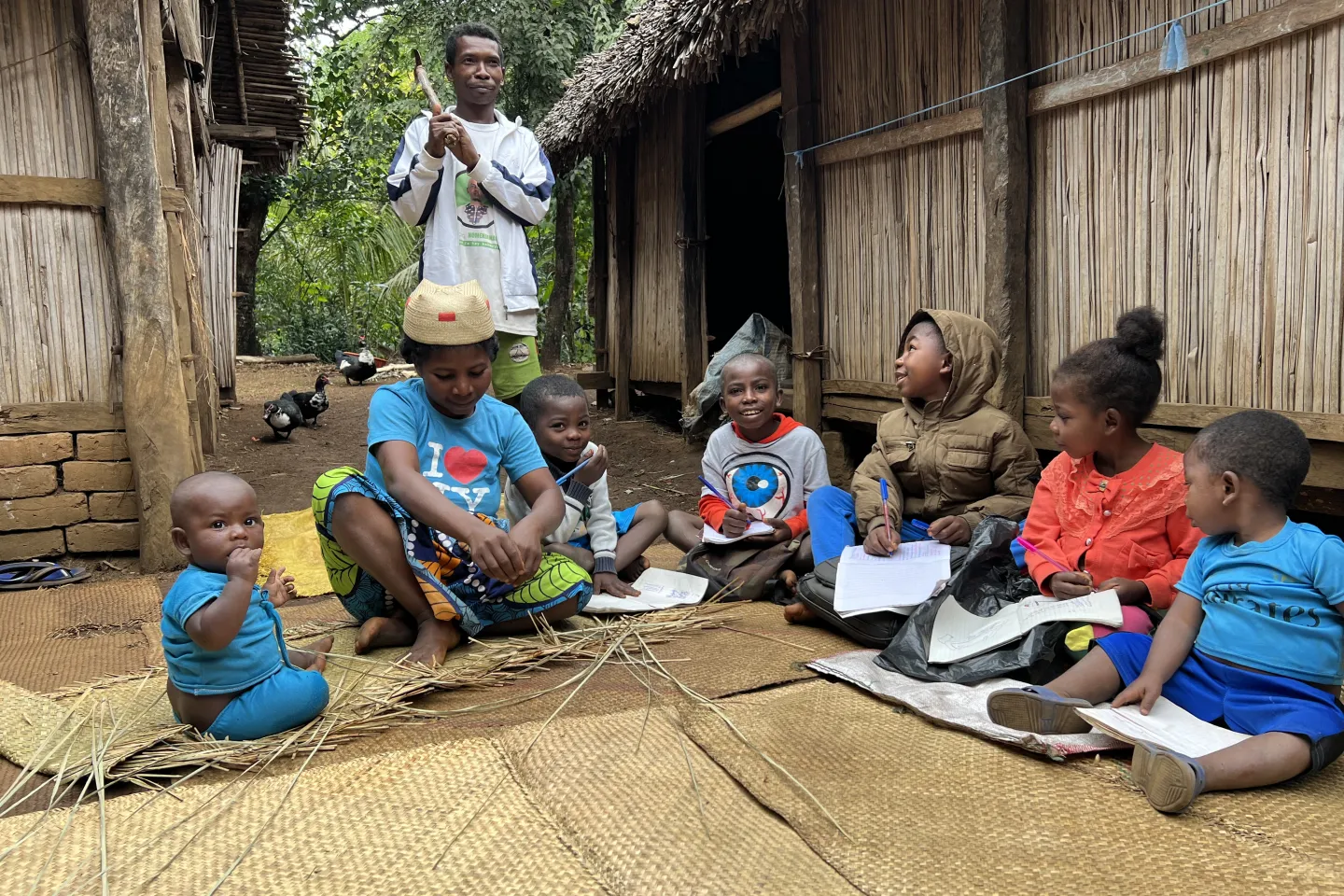 Ravololo (2eme &agrave; gauche) tisse ses nattes pendant que ses enfants lisent. Son mari Fabrice (en haut &agrave; gauche) se pr&eacute;pare &agrave; aller au travail en r&eacute;cup&eacute;rant ses outils.