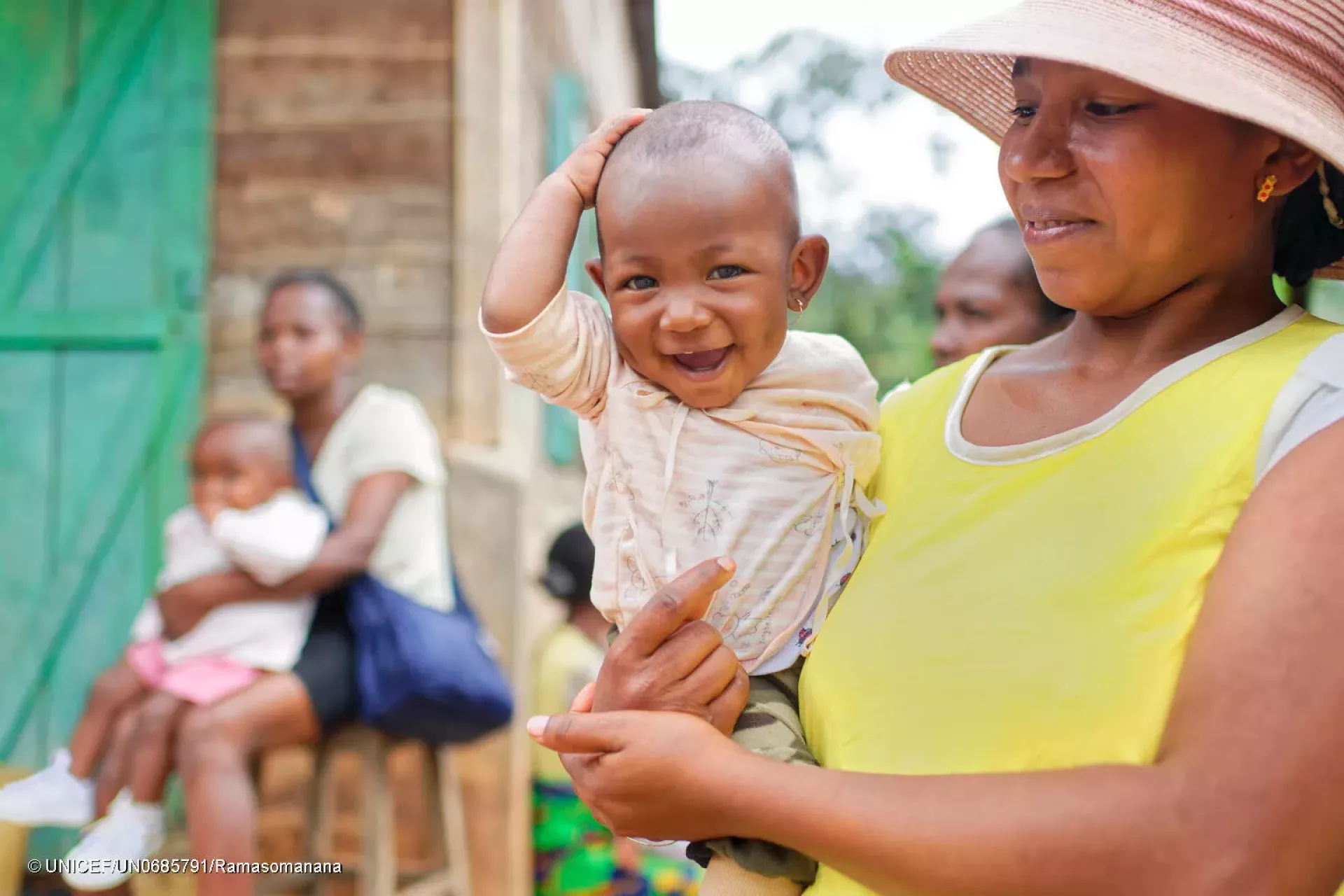 Portrait of a smiling child in the arms of his mother.
