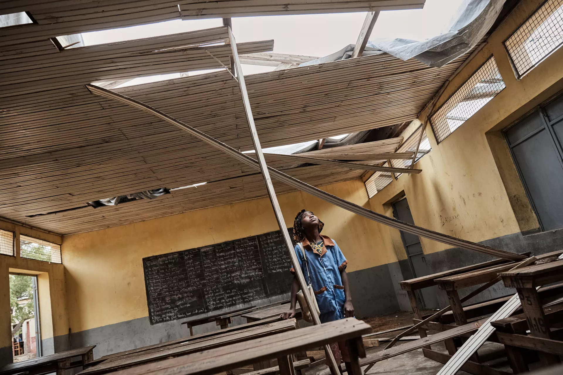 Une élève du collège d’enseignement général à Antananinarenina examinant le toit de sa salle de classe, arraché par le cyclone Freddy en mars 2023.