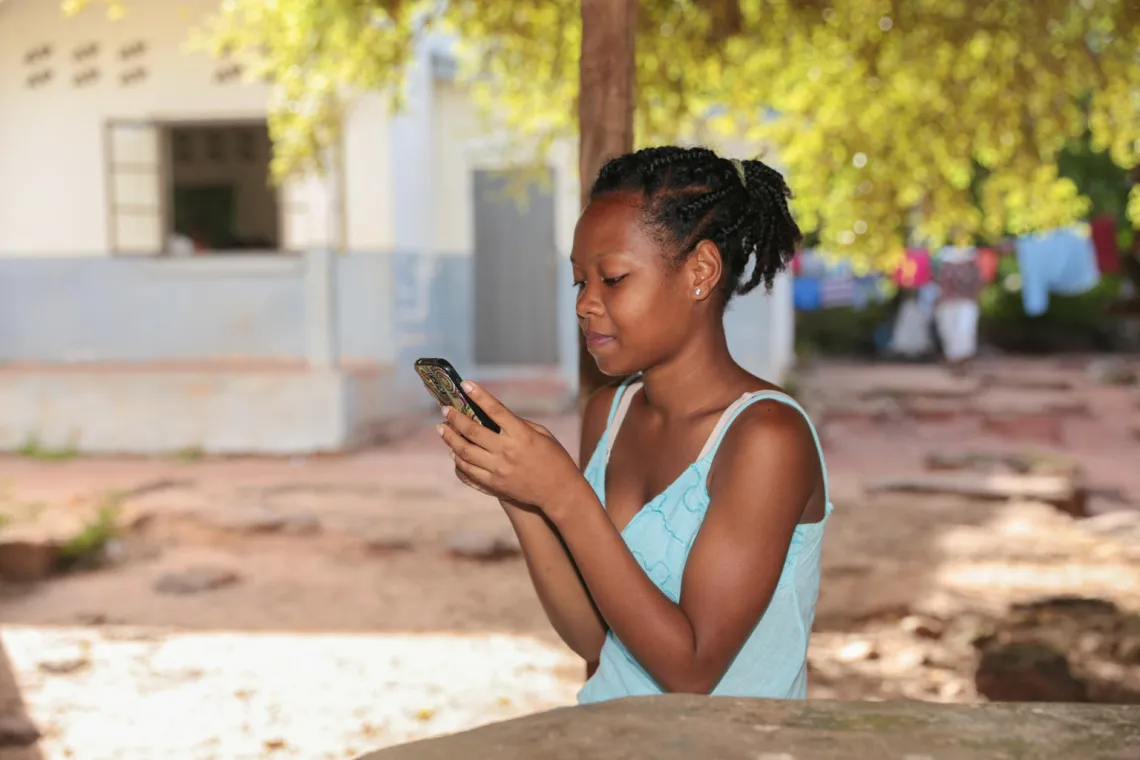 Maria joue avec son telephone portable dans la cours du coll&egrave;ge