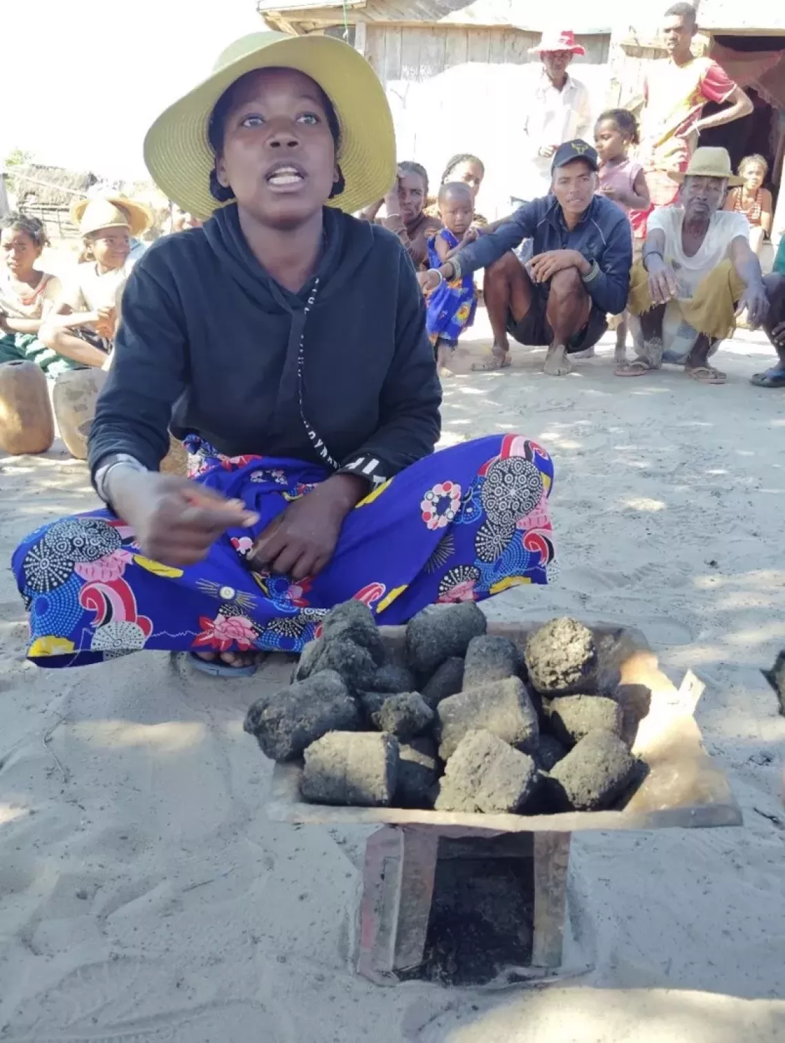 A woman explaining her process on producing charcoal made from waste materials