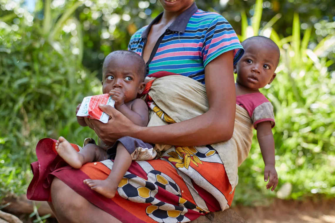 Marina, dans les bras de sa m&egrave;re, en train de manger sa ration du jour concernant le traitement de la malnutrition aigue s&eacute;v&egrave;re. 