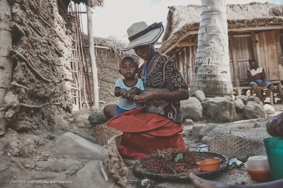 Jos&eacute;phine Kezia est assise devant chez elle avec son plus jeune enfant, Esp&eacute;r&eacute;, &acirc;g&eacute; de 18 mois. Tout en s'occupant de son fils, elle trie des grains de baie rose fra&icirc;chement r&eacute;colt&eacute;s, une activit&eacute; g&eacute;n&eacute;ratrice de revenus qui contribue &agrave; subvenir aux besoins de son foyer.