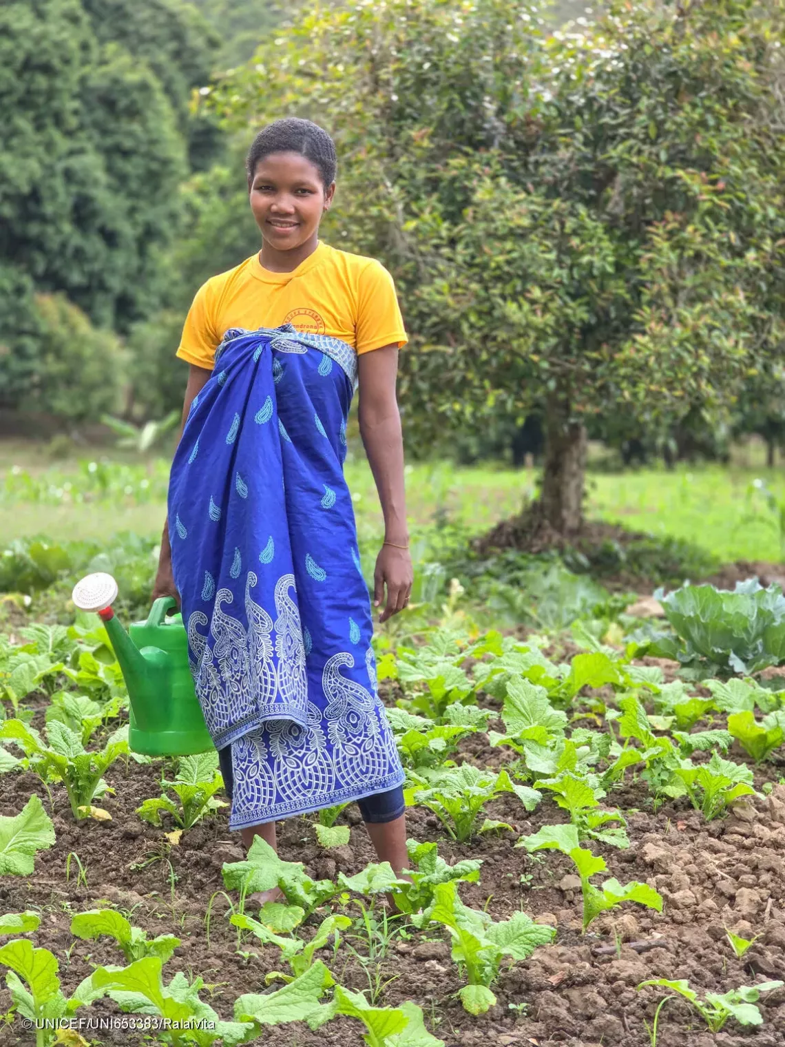 Claudia watering the vegetable field she cultivates with her husband.