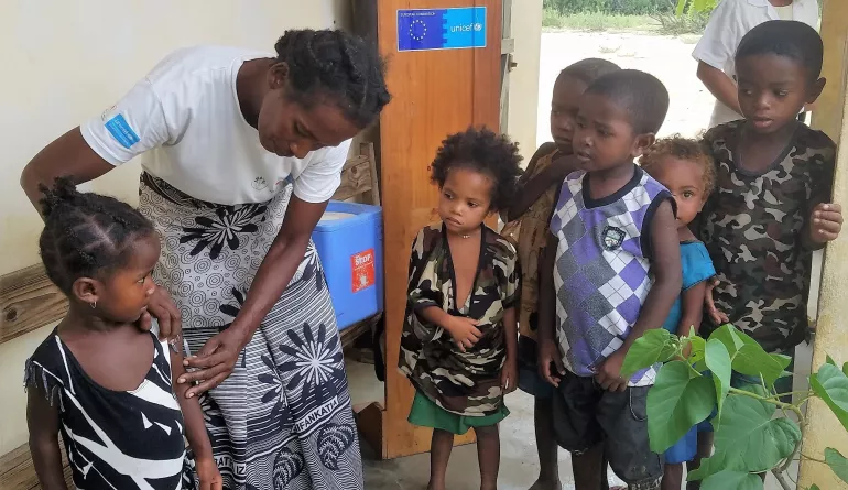 Un groupe d'enfant observe une de leurs amis qui se fait vacciner, en attendant chacun leurs tours