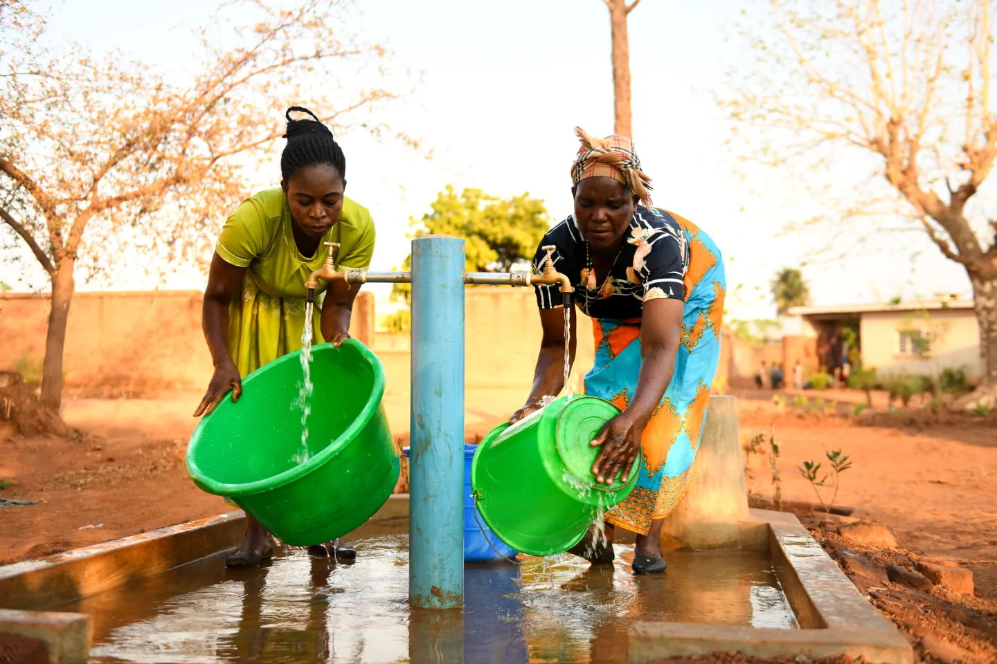 A mother and daughter collecting water at a water tap installed with support from UNICEF