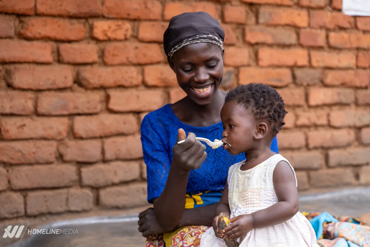 A mother feeds her child nutritious porridge in rural Lilongwe using a spoon and bowl provided by UNICEF