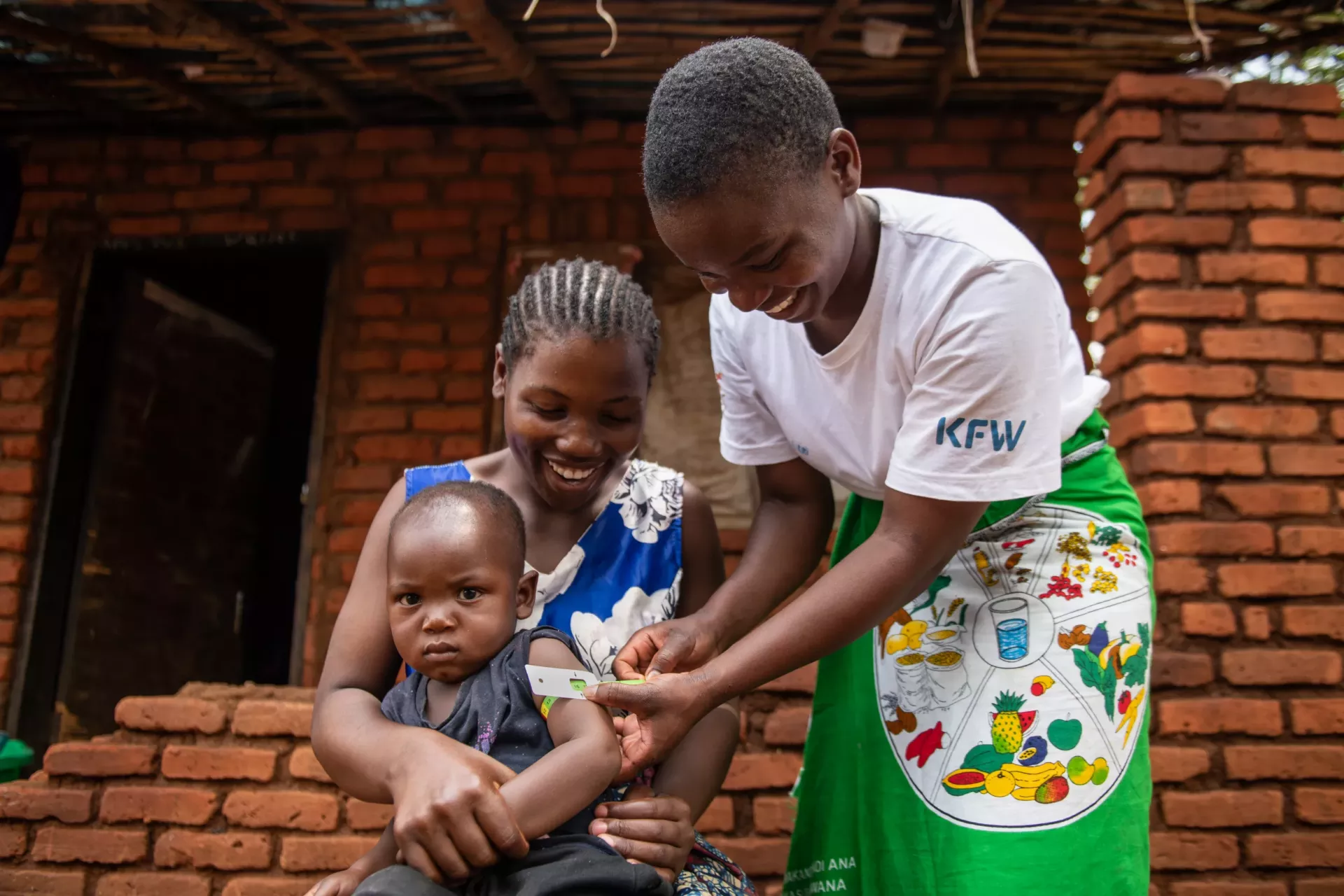 Madalitso Kasinja, a cluster leader screens 19 months old Marvelous Austin using MUAC tape at Light Village in Blantyre, southern Malawi. 
