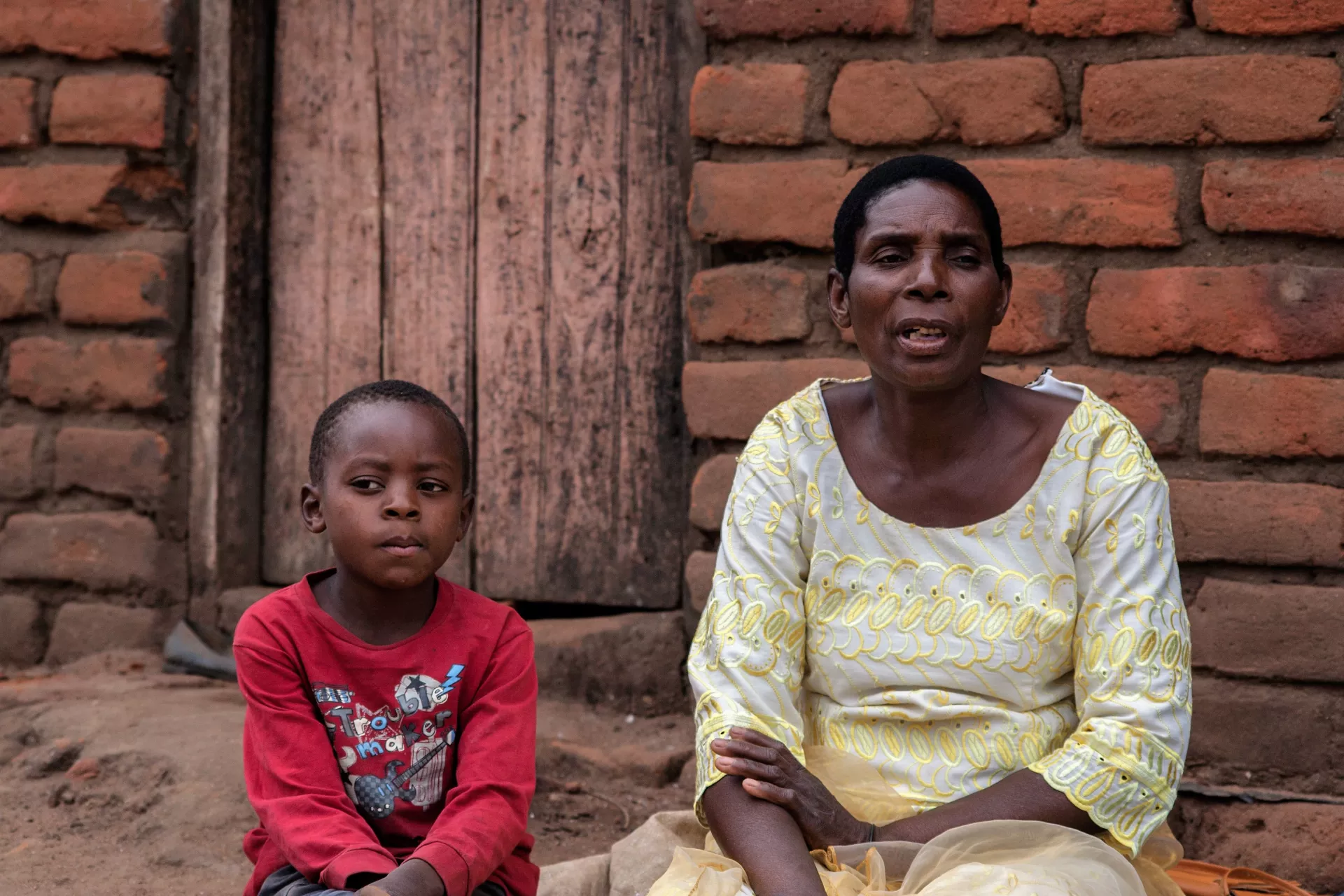 Eliza James with her son outside their home in Balaka  