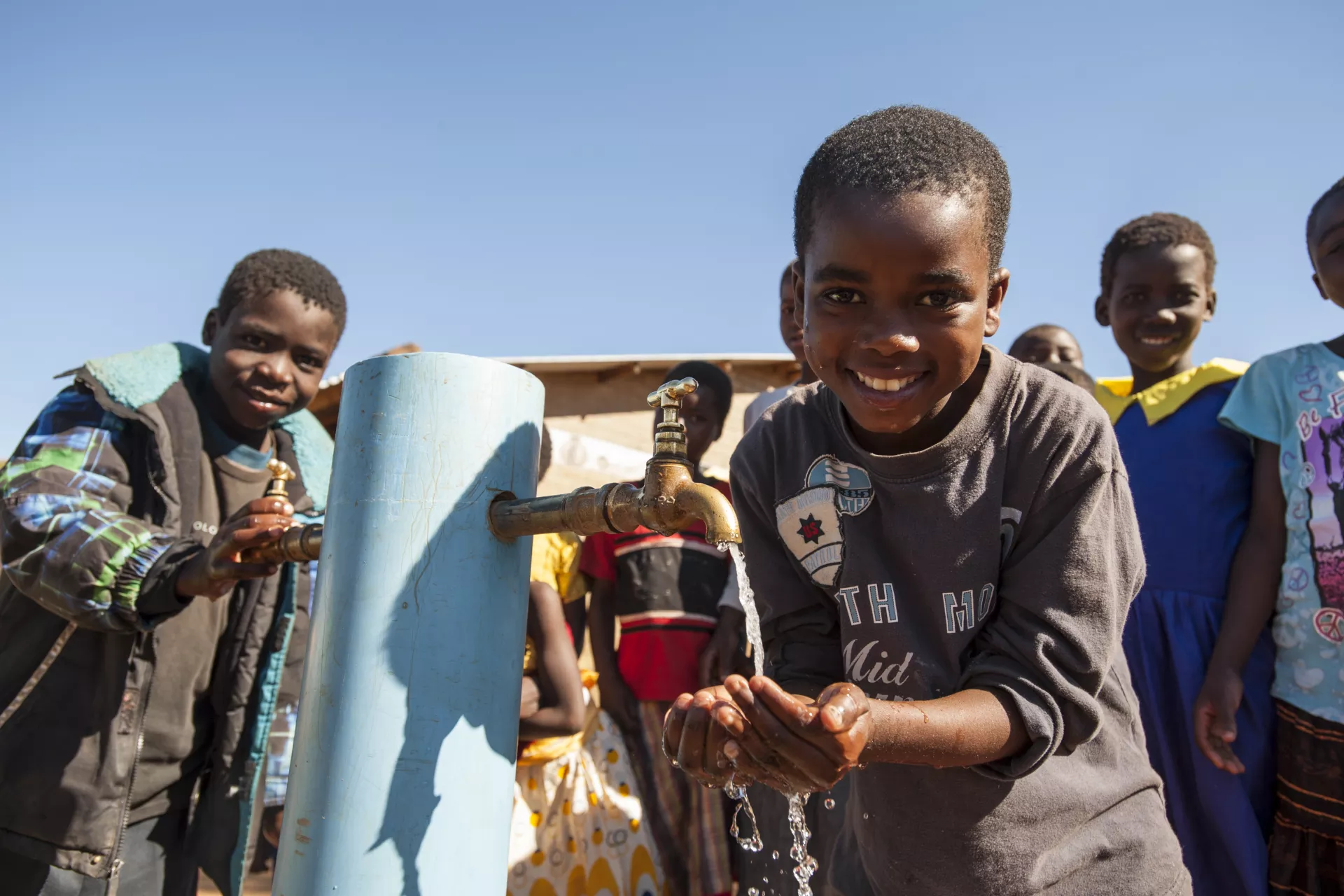A little boy drinks water at a primary school in Blantyre