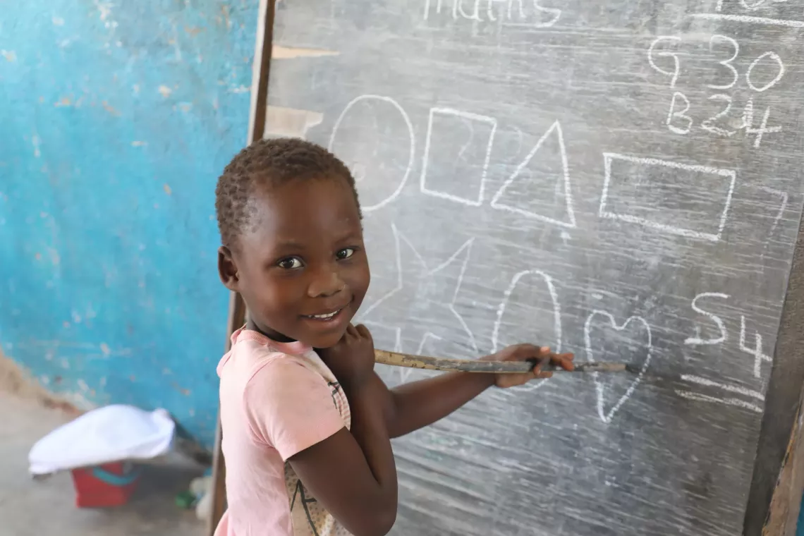 A child at the CBCC is seen writing on a chalk board