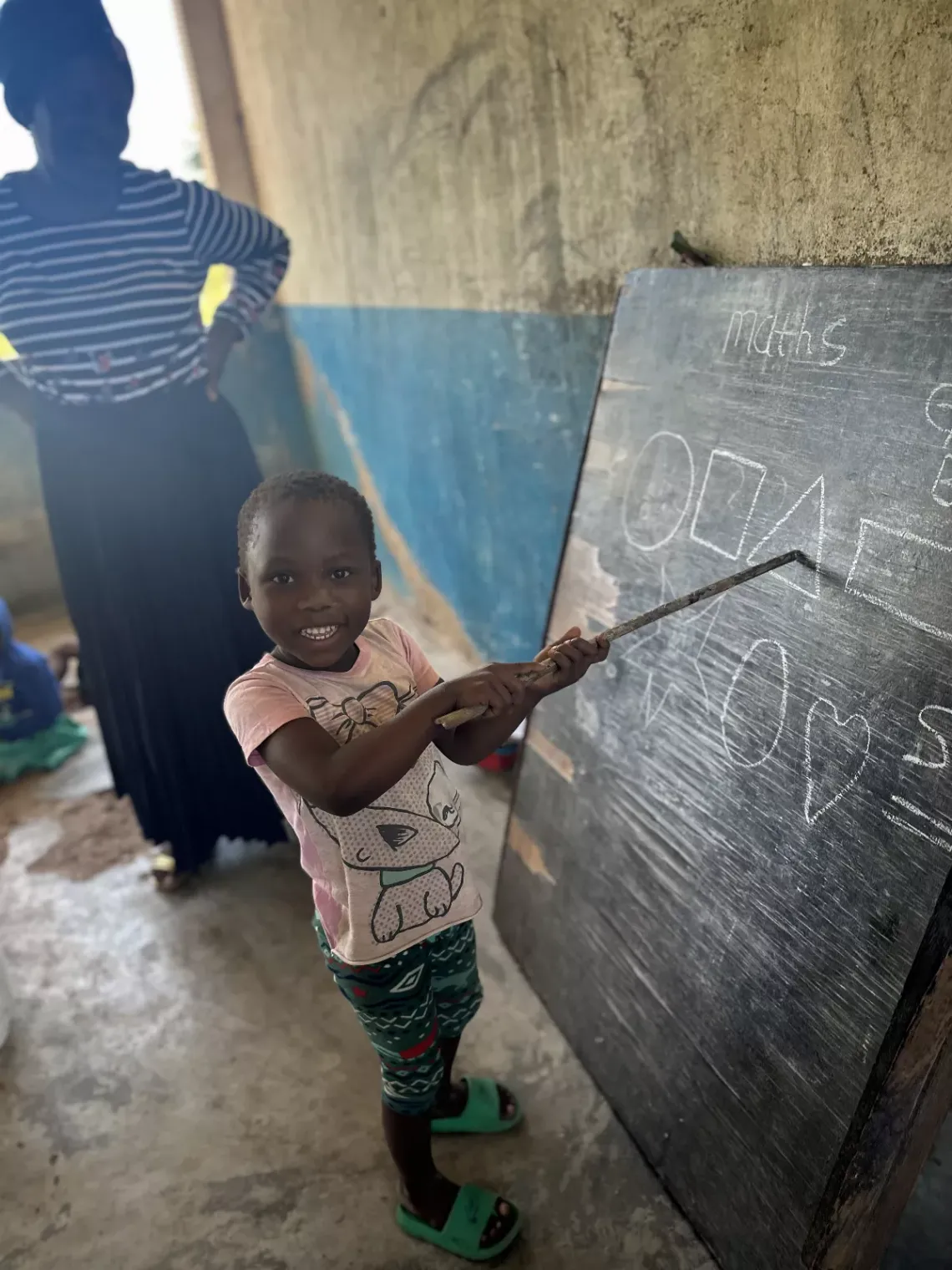 A child with all smiles is seen learning happily in a classroom at Jonasi CBCC