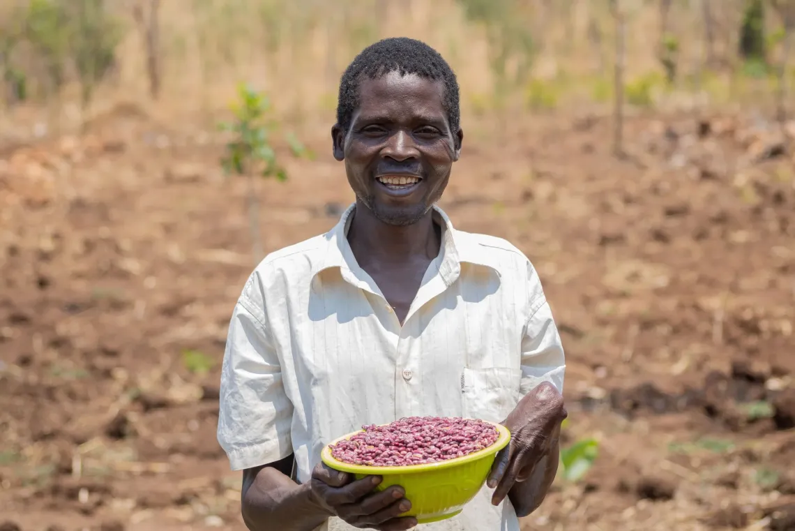 Michael Benedict of Lindadi Village, TA Kambwiri, Salima, displays harvested dried beans