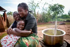A mother cooking with her two children in Gunde village, Thyolo