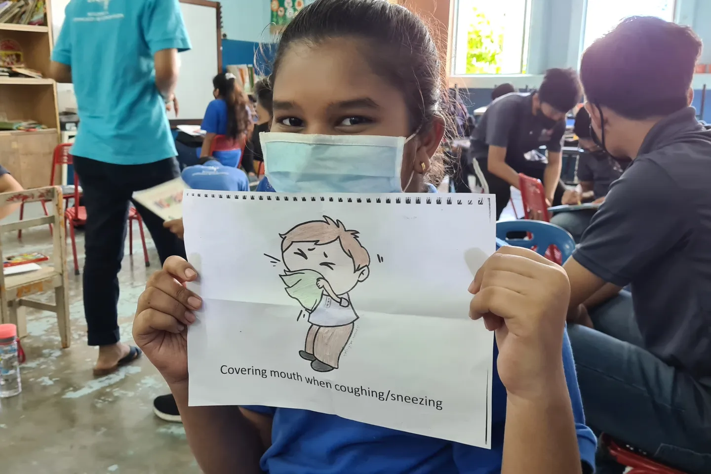 A masked girl holding drawing of sneezing figure
