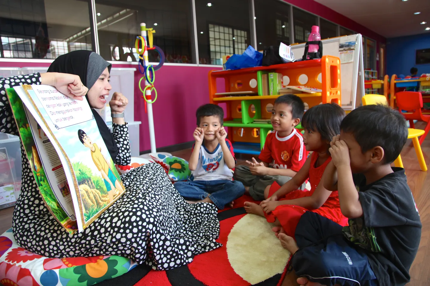 children sitting around teacher listening