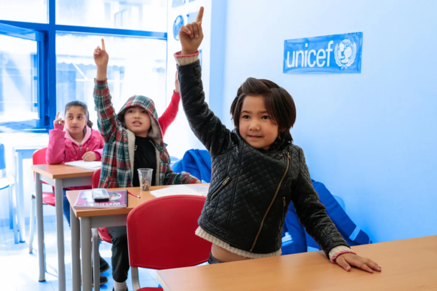 children in class raising their hands