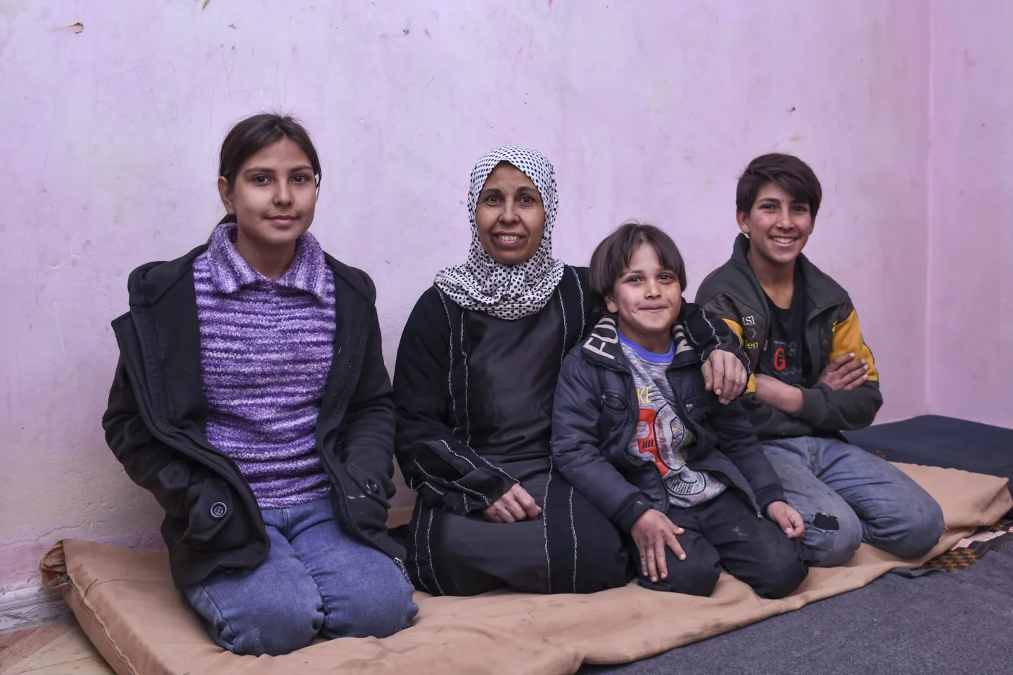 Farha, 45, sits surrounded by her children, Majd, 15, Esraa, 14, and Hussein, 6, in their apartment in Shabaa village, Rural Damascus, Syria, on 7 January 2025.