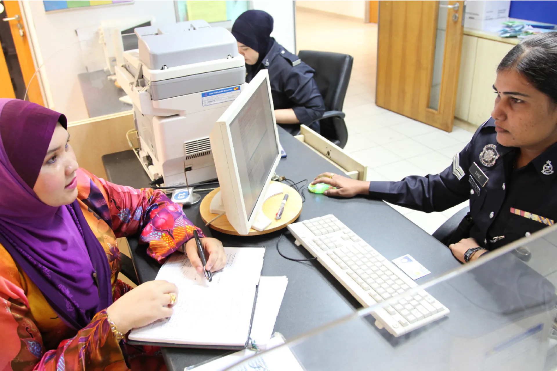 A social worker from the Department of Social Welfare lodges a report of child abuse with an officer at the police station