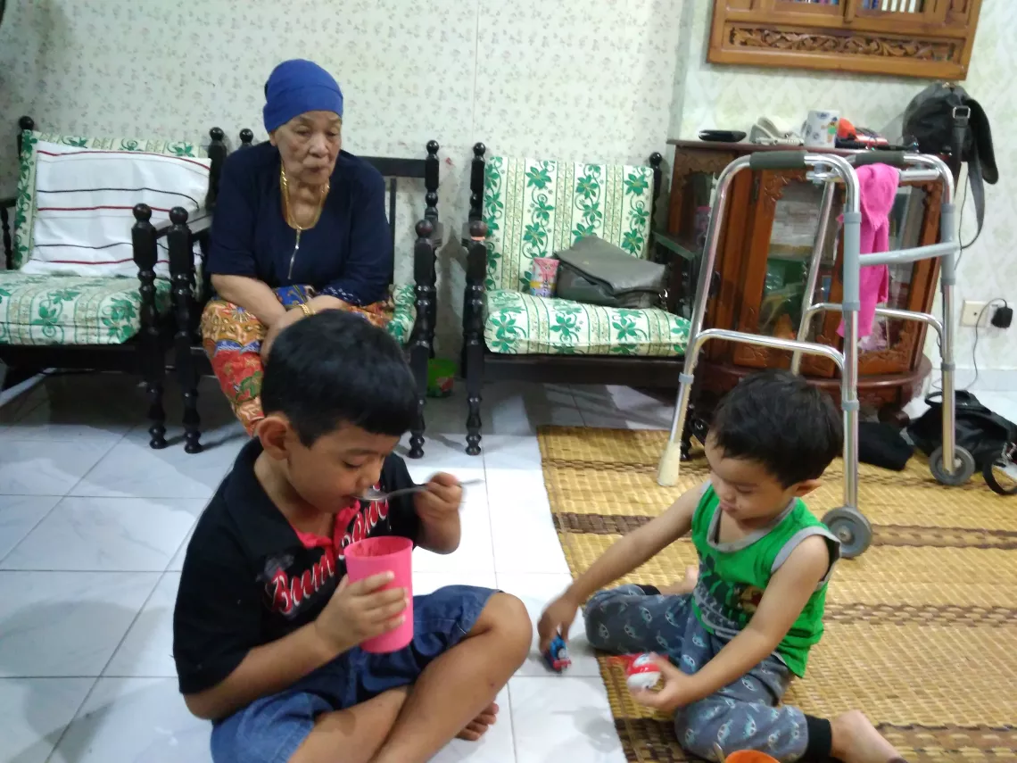 Two young boys playing whilst grandma watches