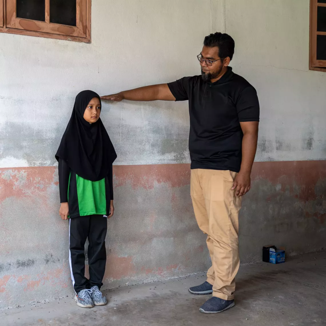 Abe Ha, points to the floodwater mark on their home in Rantau Panjang, Kelantan, a striking reminder of when the water rose to the same height as his daughter, Ameera.