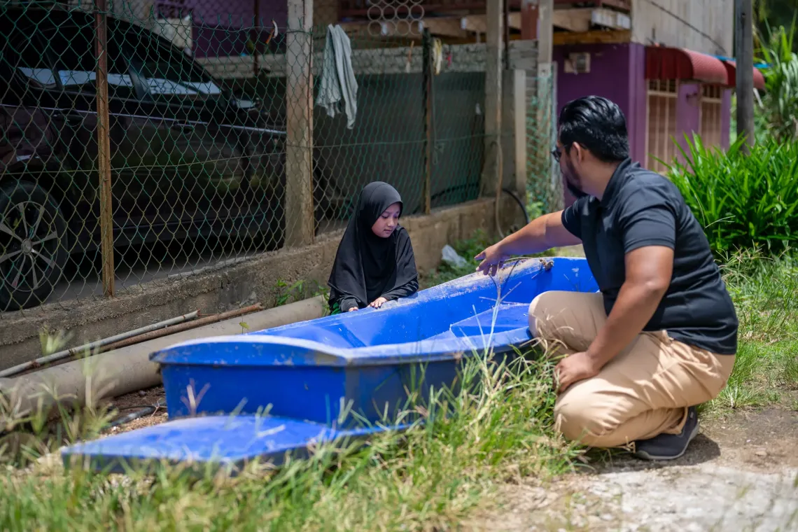 Ameera and her father, Mohammad Hafiz fondly known as Abe Ha, showing their small boat, which they use during floods, at their home in Rantau Panjang, Kelantan.