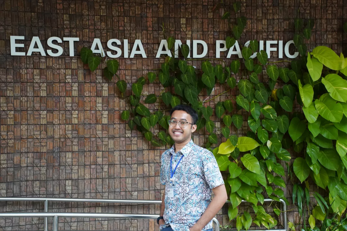 Youth advocate smiling in front of leaf covered wall