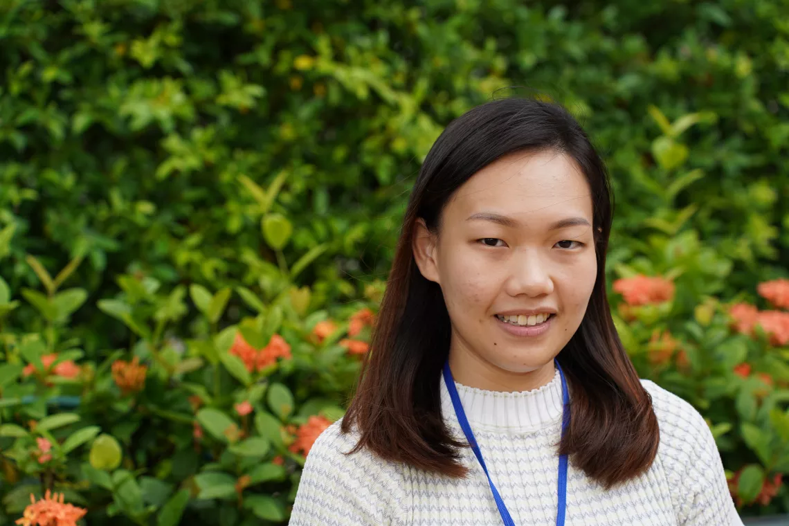 Youth advocate smiling in front of leaf covered wall