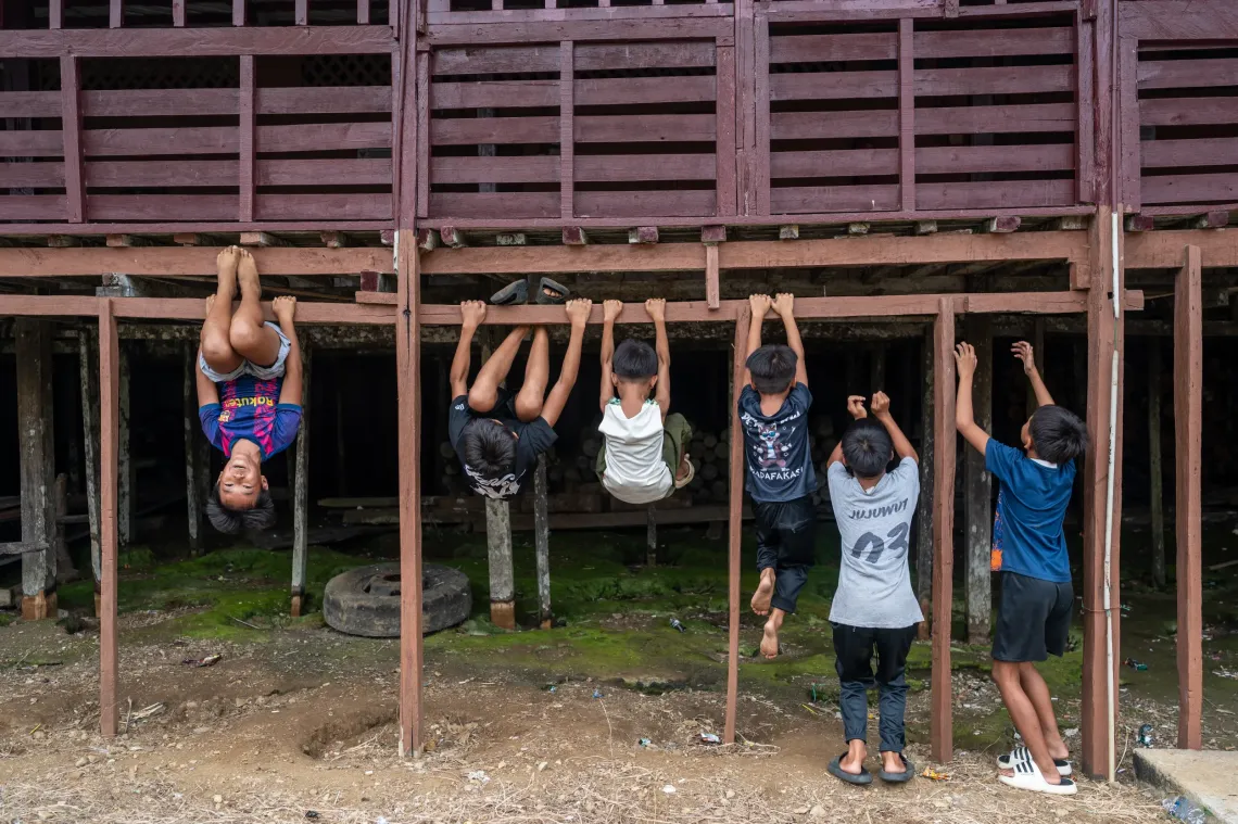 Children play and climb on the wooden structure of a longhouse in Serian, Sarawak.