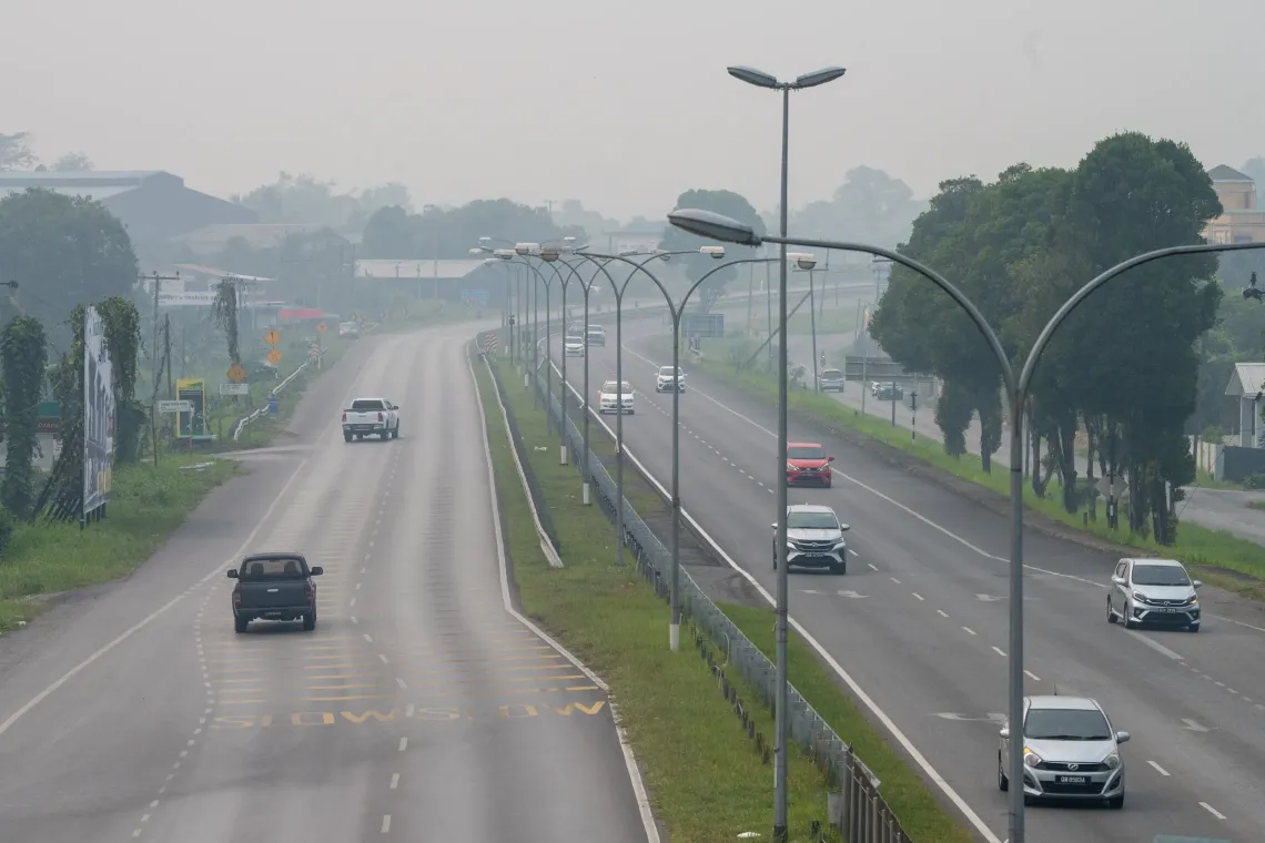 A highway stretches through Serian, Sarawak, as haze blankets the surrounding landscape and obscures the distance