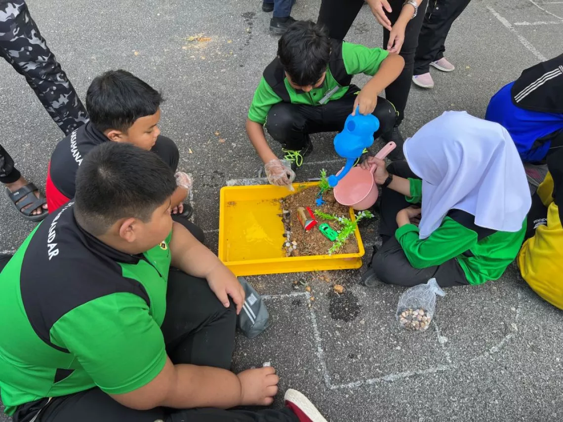 Four students playing with miniatures resembling a landslide disaster.