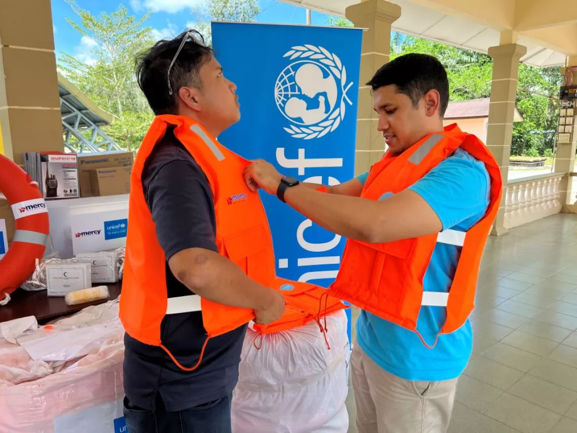 Mercy Malaysia and UNICEF Staff do a demo on properly wearing a life jacket.