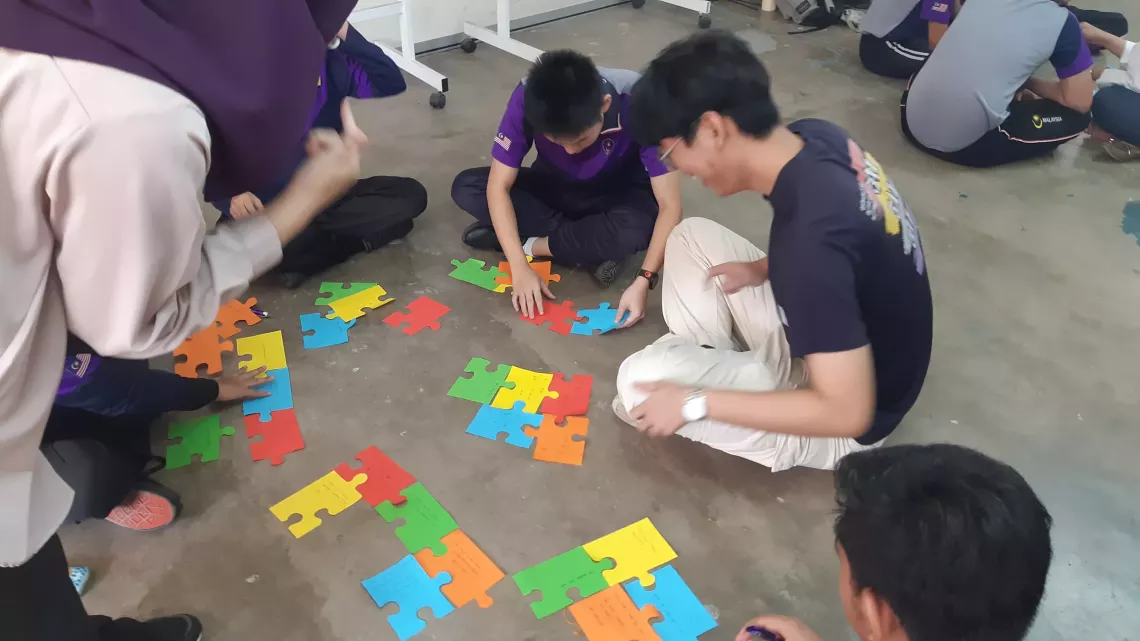 Teens arranging the pieces to a paper jigsaw
